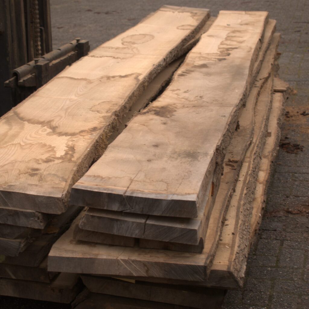 Stapel essenhouten planken op het landgoed van Hard & Zachthout, ideaal voor meubelbouw en timmerprojecten